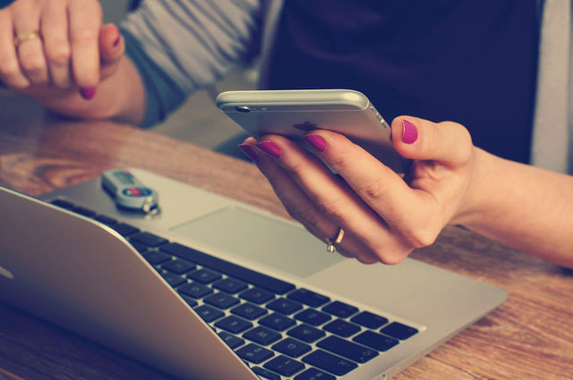 スマホを参照しながらPCで作業する女性