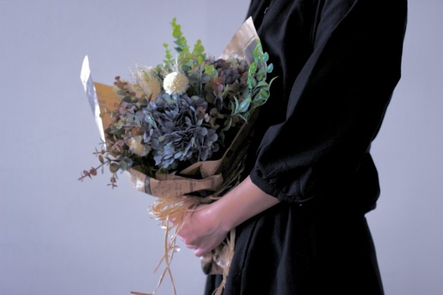 黒い服を着て花束を持つ人