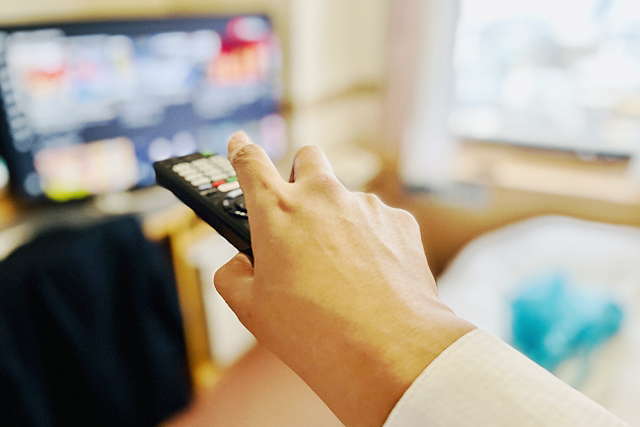 テレビの画面とリモコンを持つ手