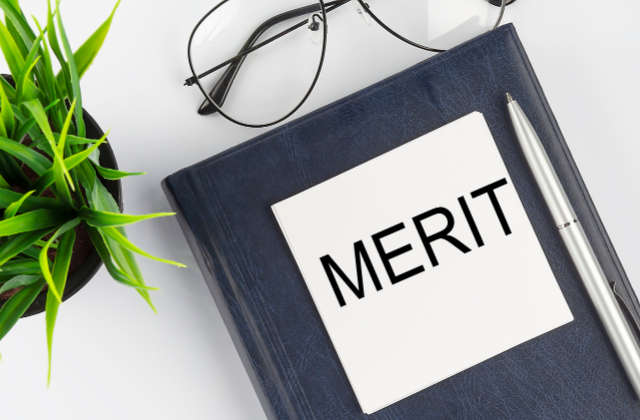 白い背景に植物とメガネとMERITと書かれた本とペン