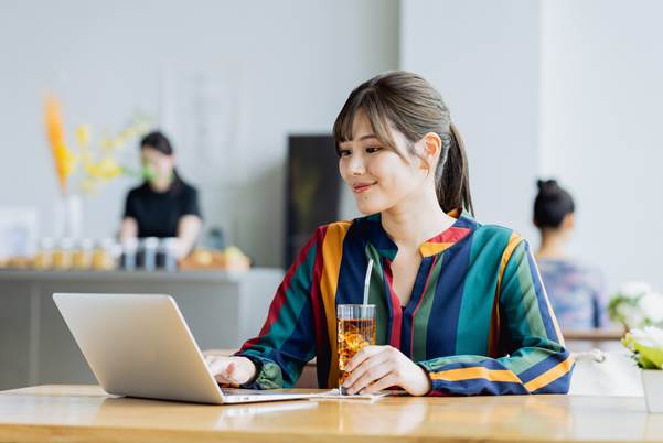 飲み物を飲みながらパソコンを操作する女性