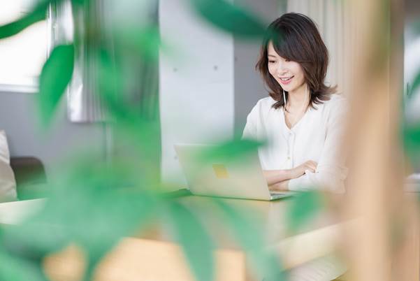 イヤホンをしながらパソコンを見る女性