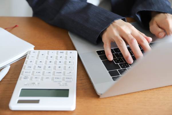 パソコンと電卓を操作する人の手元
