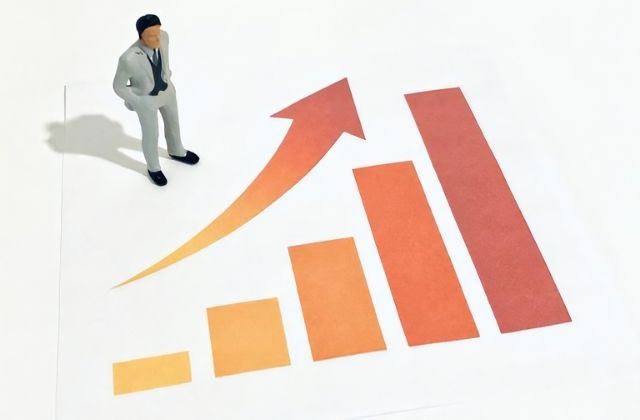 右肩上がりのグラフとミニチュア男性