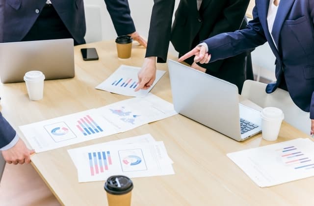 大人が資料を指さして会議している様子