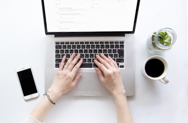 机の上にパソコンと携帯とコーヒー