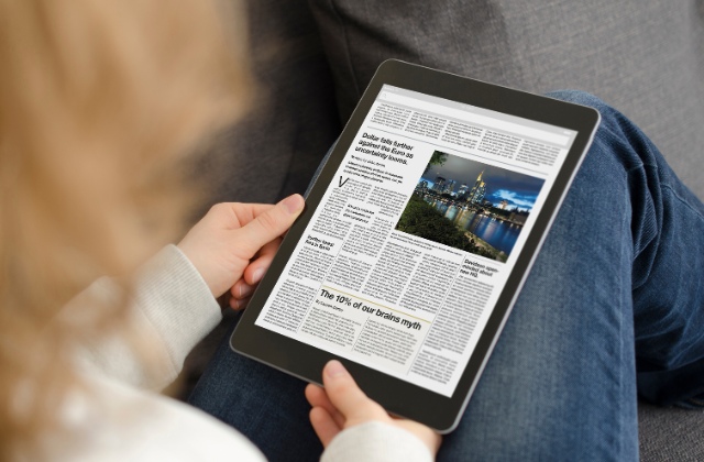 タブレットで新聞を読んでいる人の写真